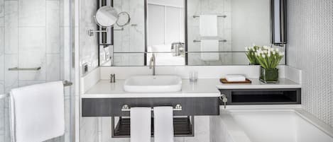 Un baño moderno con un espejo grande, un lavamanos blanco y una cabina de ducha de vidrio.