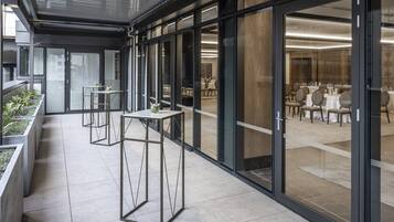 A modern hotel corridor with glass doors leading to a dining area.