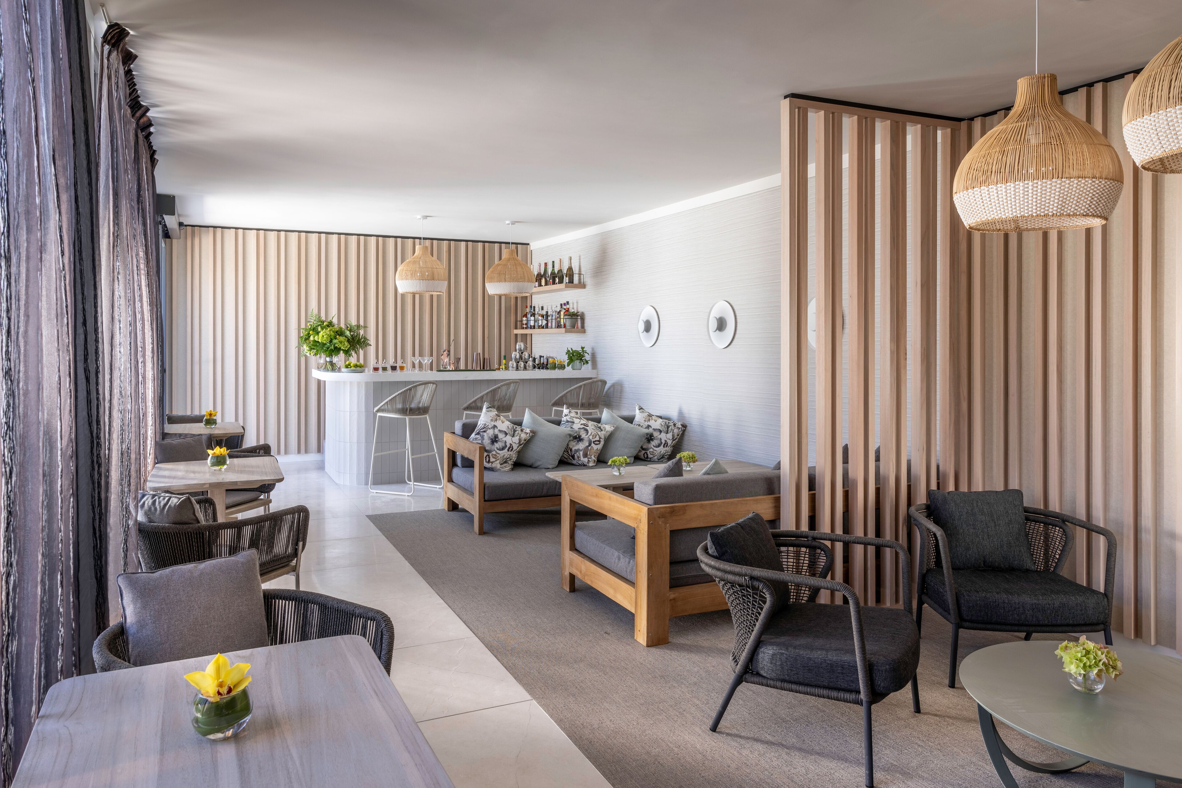 A modern living room with a sofa, chairs, a coffee table, and a dining area with a bar.