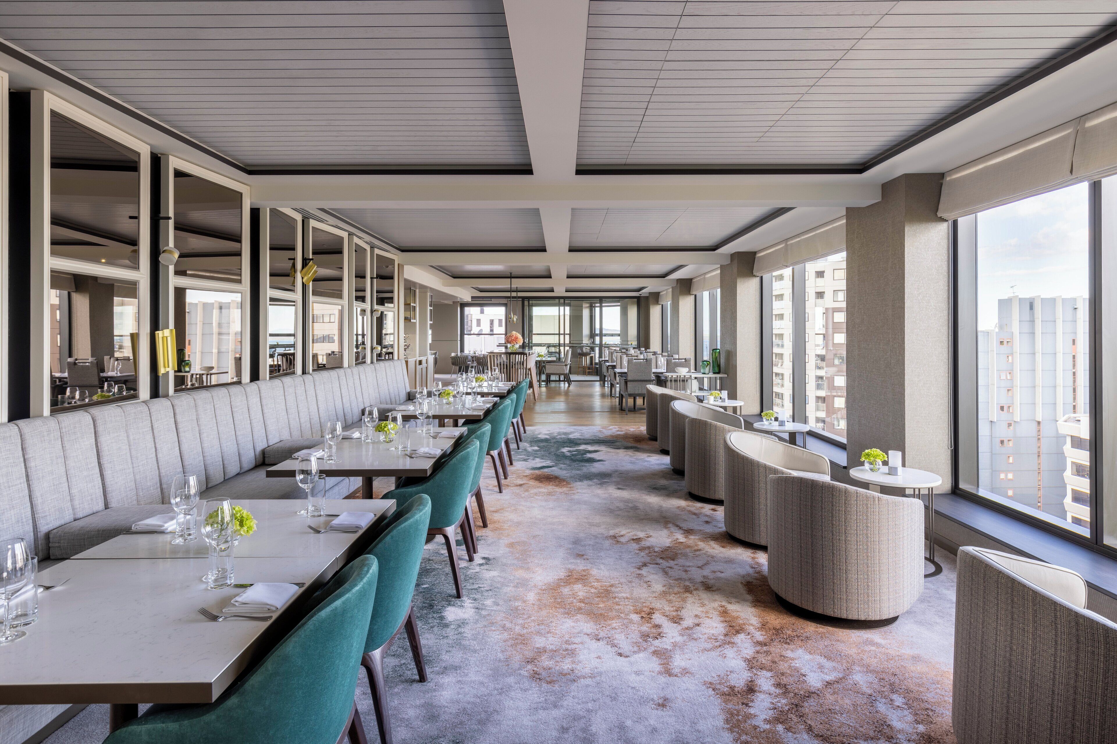 A modern restaurant with high ceilings, long tables, and comfortable seating.