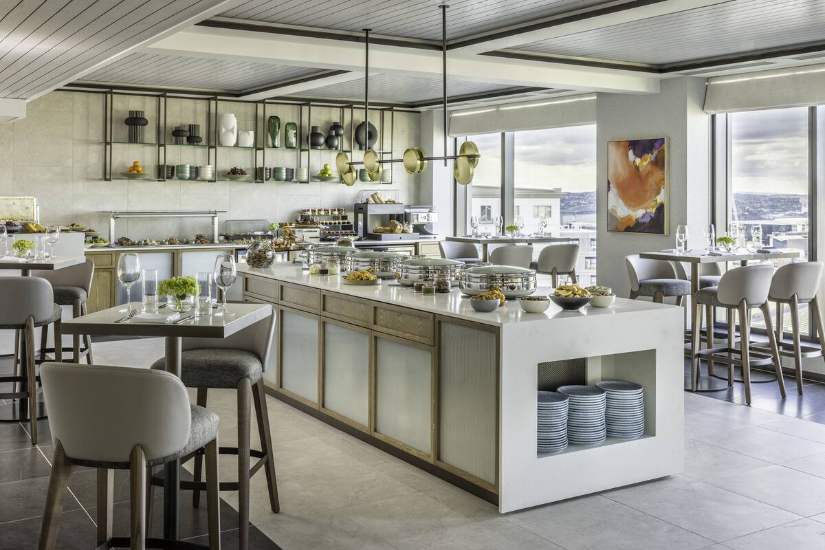 A modern kitchen with a central island, bar stools, and a view of the city.