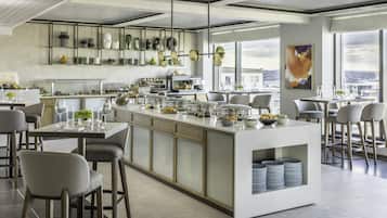 A modern kitchen with a central island, bar stools, and a view of the city.