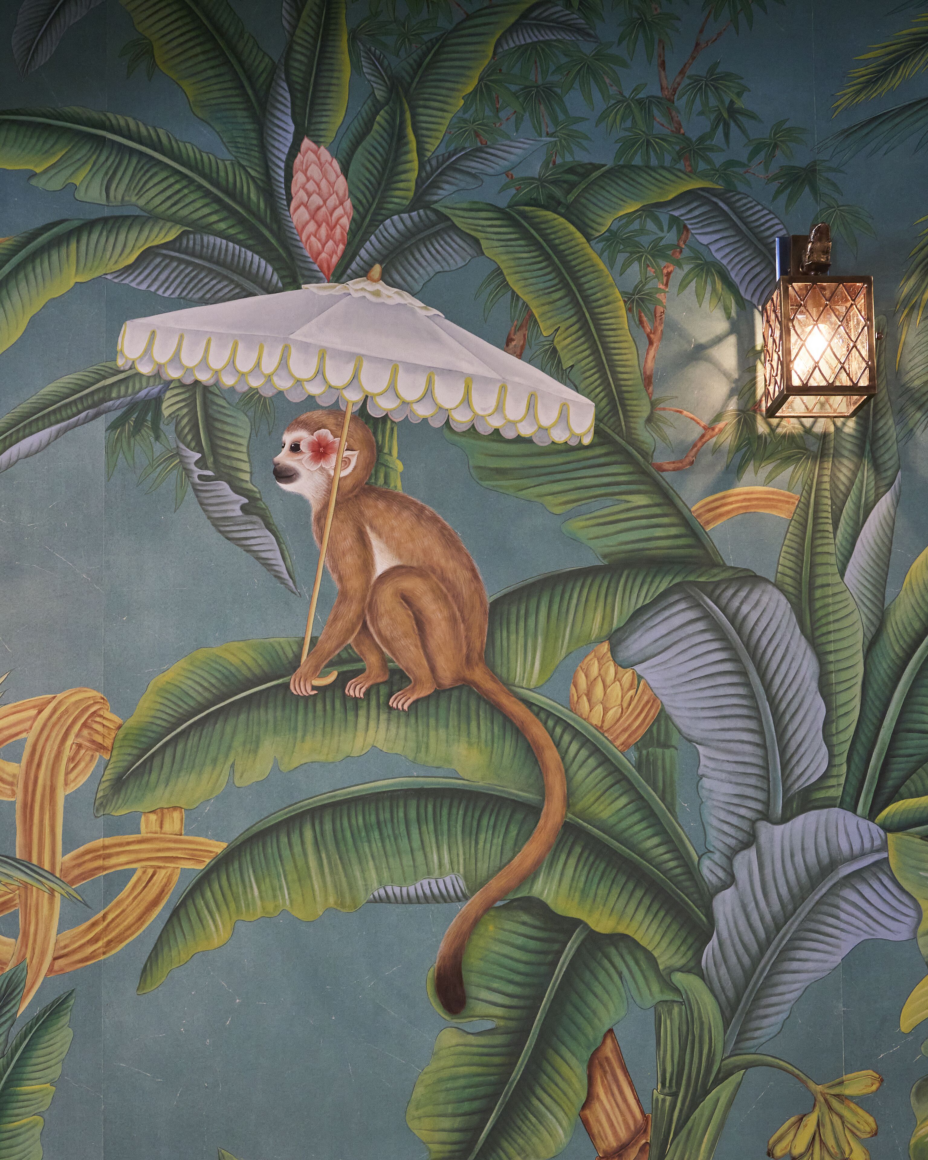 Um mural com um macaco sob uma palmeira, um lanterna pendurada e folhagem tropical.