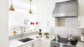Una cocina moderna con armarios blancos, electrodomésticos de acero inoxidable y azulejos decorativos en la pared.