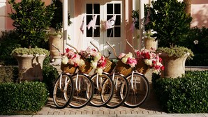 A building with a large, ornate entrance canopy, a series of potted plants, and bicycles with flower baskets parked in front. - The Colony Hotel Palm Beach (Palm Beach)