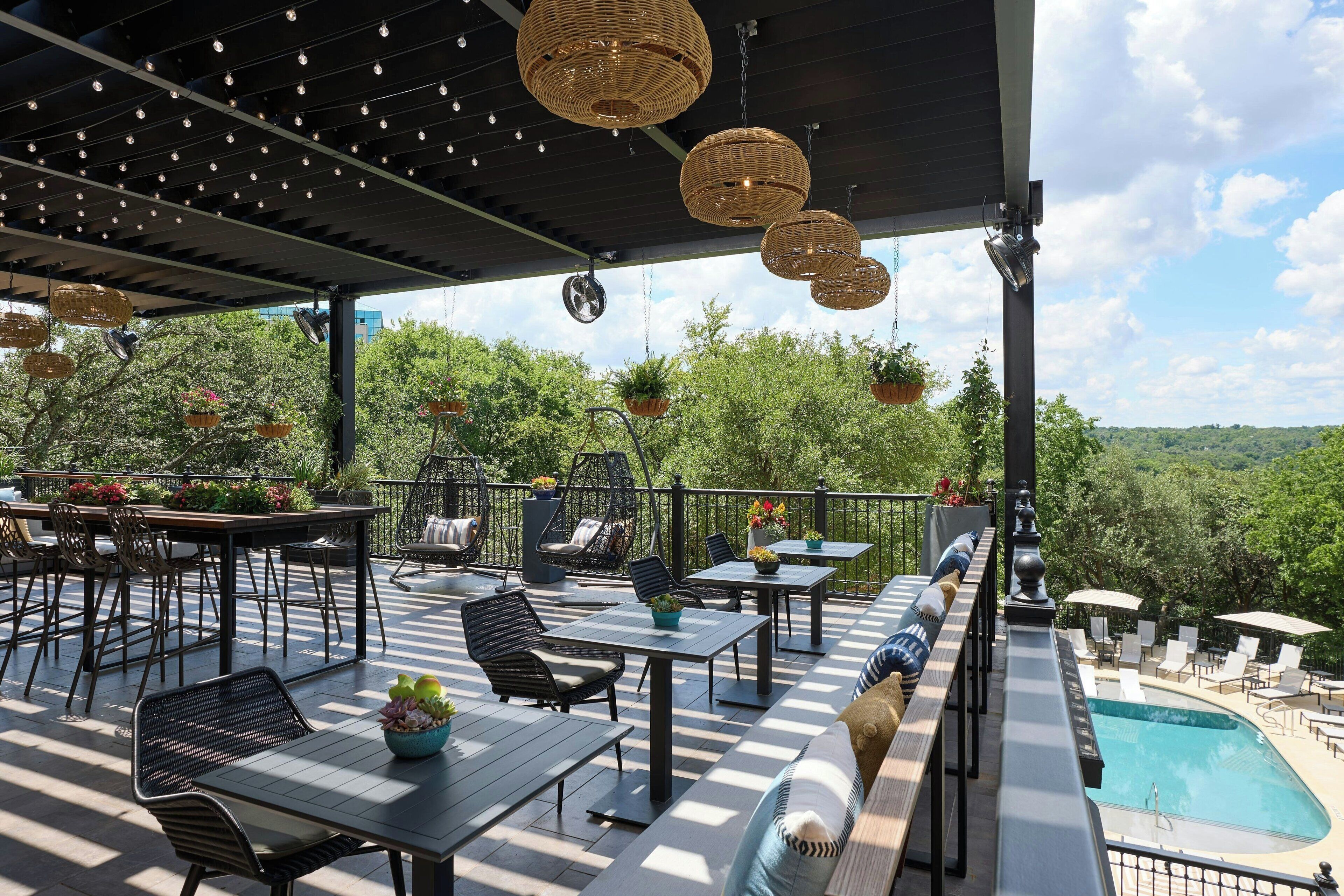 An outdoor patio with tables and chairs, a pool, and hanging planters. - Renaissance Austin Arboretum Domain Hotel (Austin)