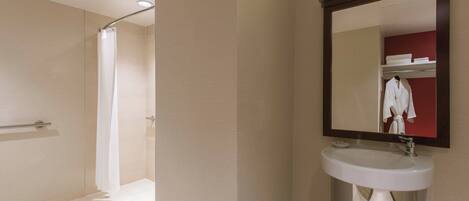 A modern bathroom with a shower, a sink, and a mirror.