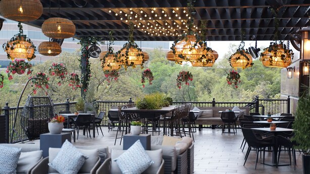 An outdoor patio with wicker furniture, hanging wicker lamps, and potted plants. - Renaissance Austin Arboretum Domain Hotel (Austin)