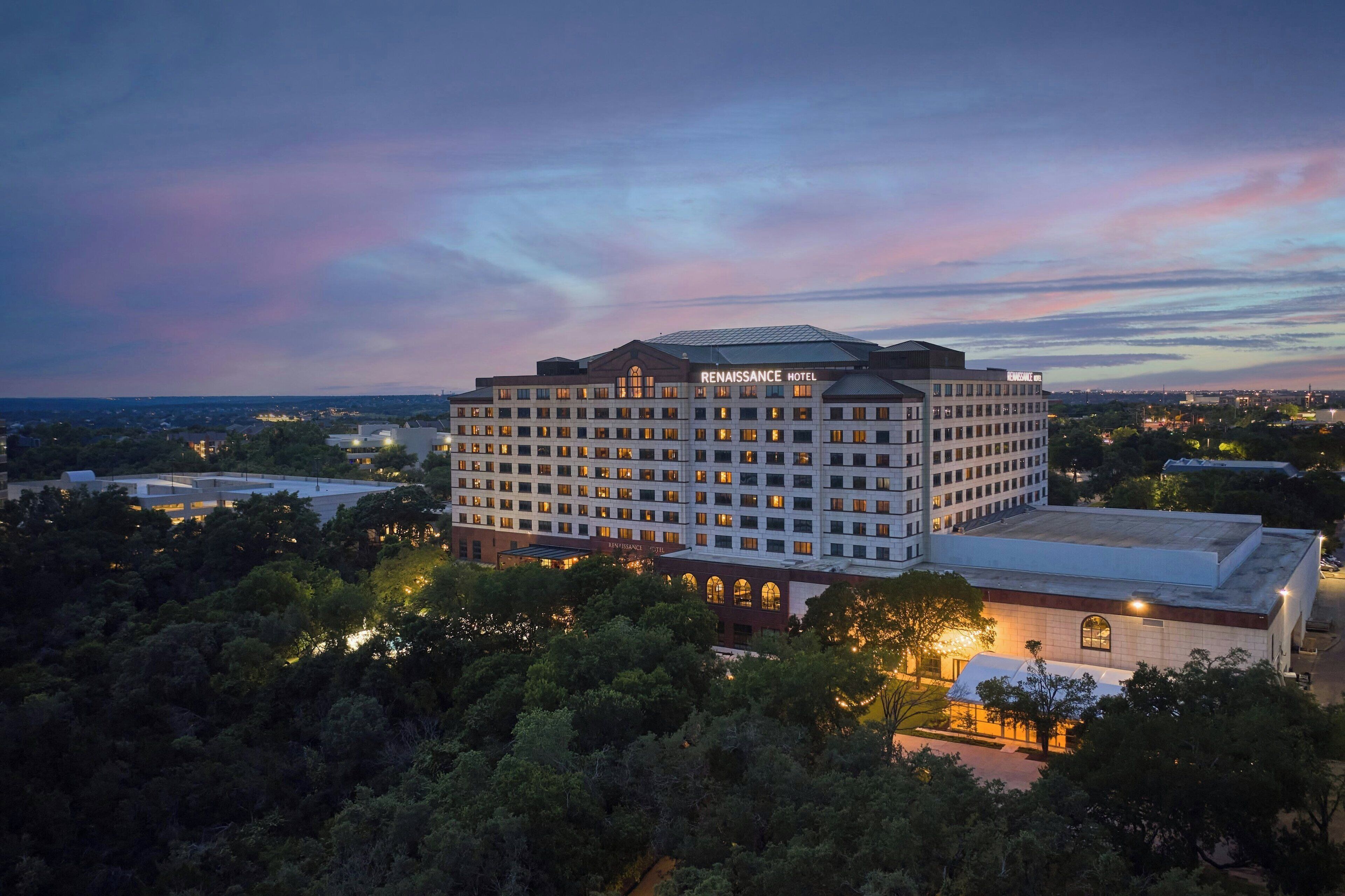 Ein Renaissance Hotel mit einem großen, mehrstöckigen Gebäude, umgeben von Bäumen und anderen Häusern.