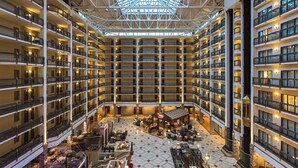 A multi-level hotel atrium with a central open space, multiple balconies, and a variety of seating areas. - Renaissance Austin Arboretum Domain Hotel (Austin)