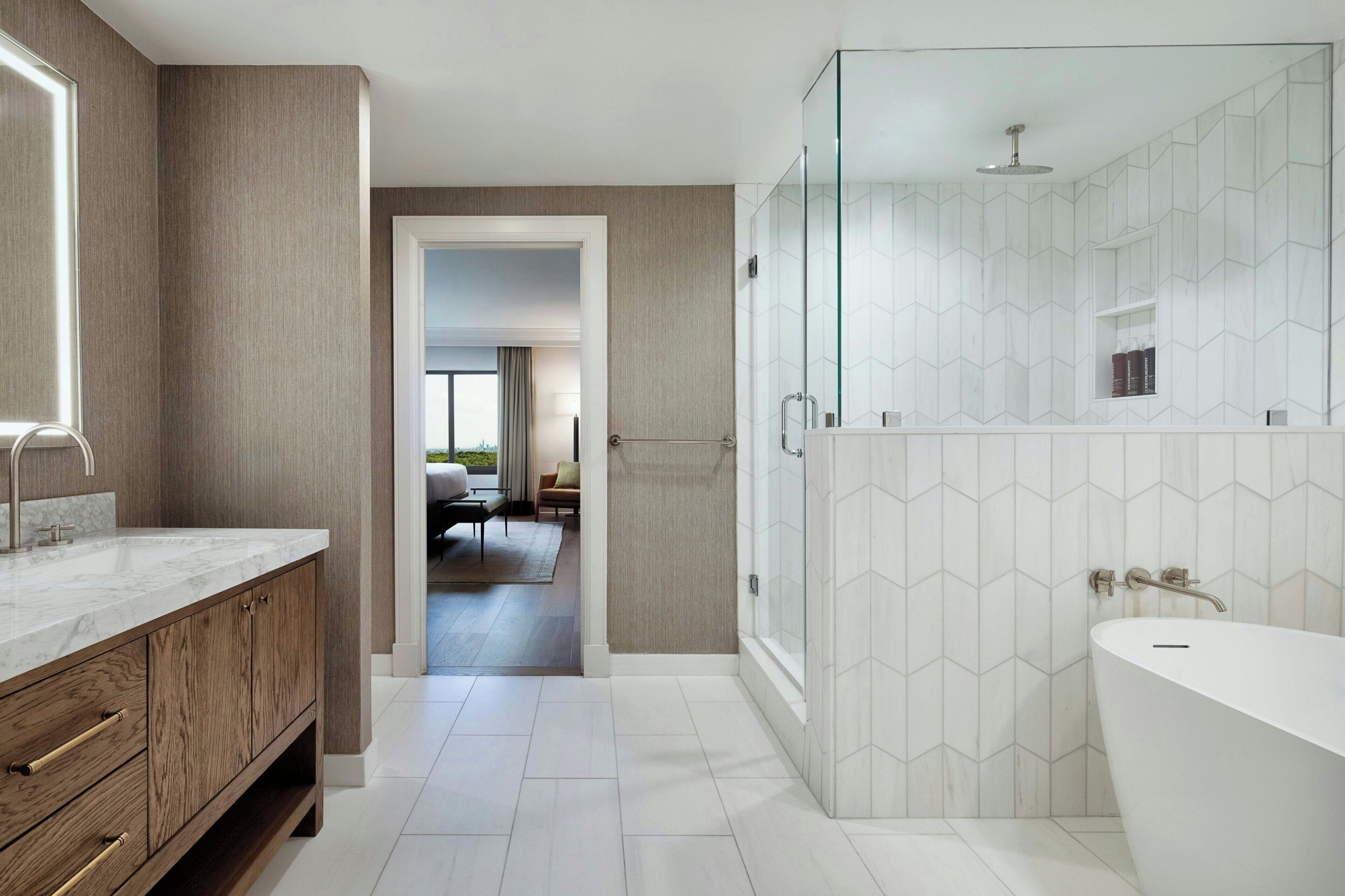 Une salle de bain moderne avec une baignoire sur pieds, une douche à parois de verre et un meuble-lavabo doté d'un plan de travail en marbre.