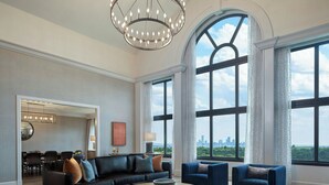 A spacious living room with a large chandelier, a round coffee table, and a view of the city skyline through large windows. - Renaissance Austin Arboretum Domain Hotel (Austin)