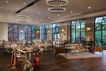 An outdoor patio with tables and chairs, a pool, and hanging planters. at Renaissance Austin Arboretum Domain Hotel