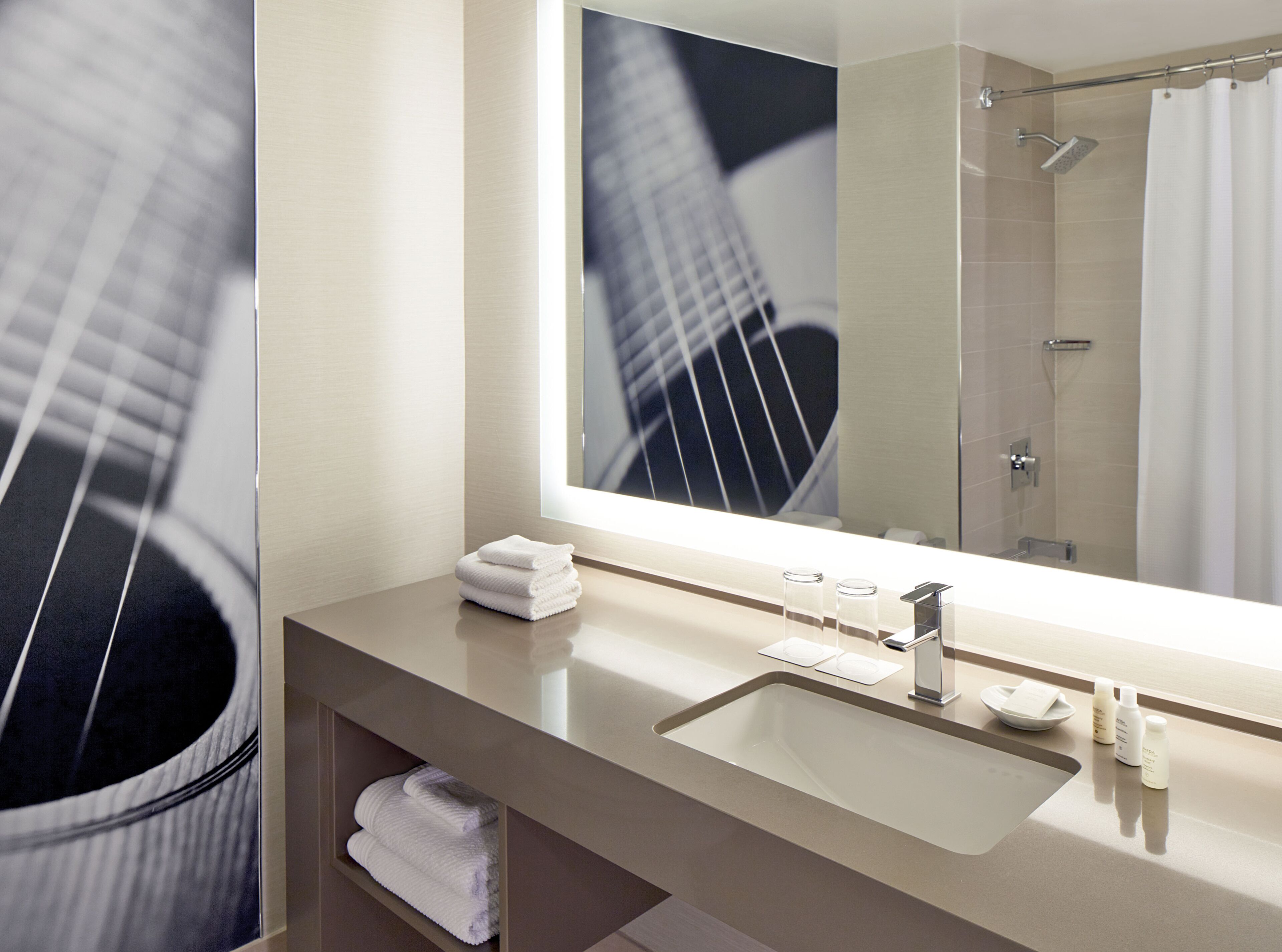 A modern bathroom with a large mirror, a sink, and a shower.