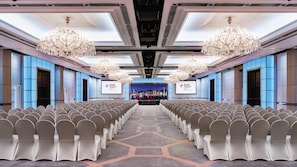A conference room with rows of chairs, a large screen at the front, and chandeliers. - Holiday Inn Golden Mile Hong Kong by IHG (Kowloon)