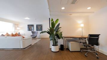 A modern office space with a white sofa, a desk, a black office chair, and a potted plant.