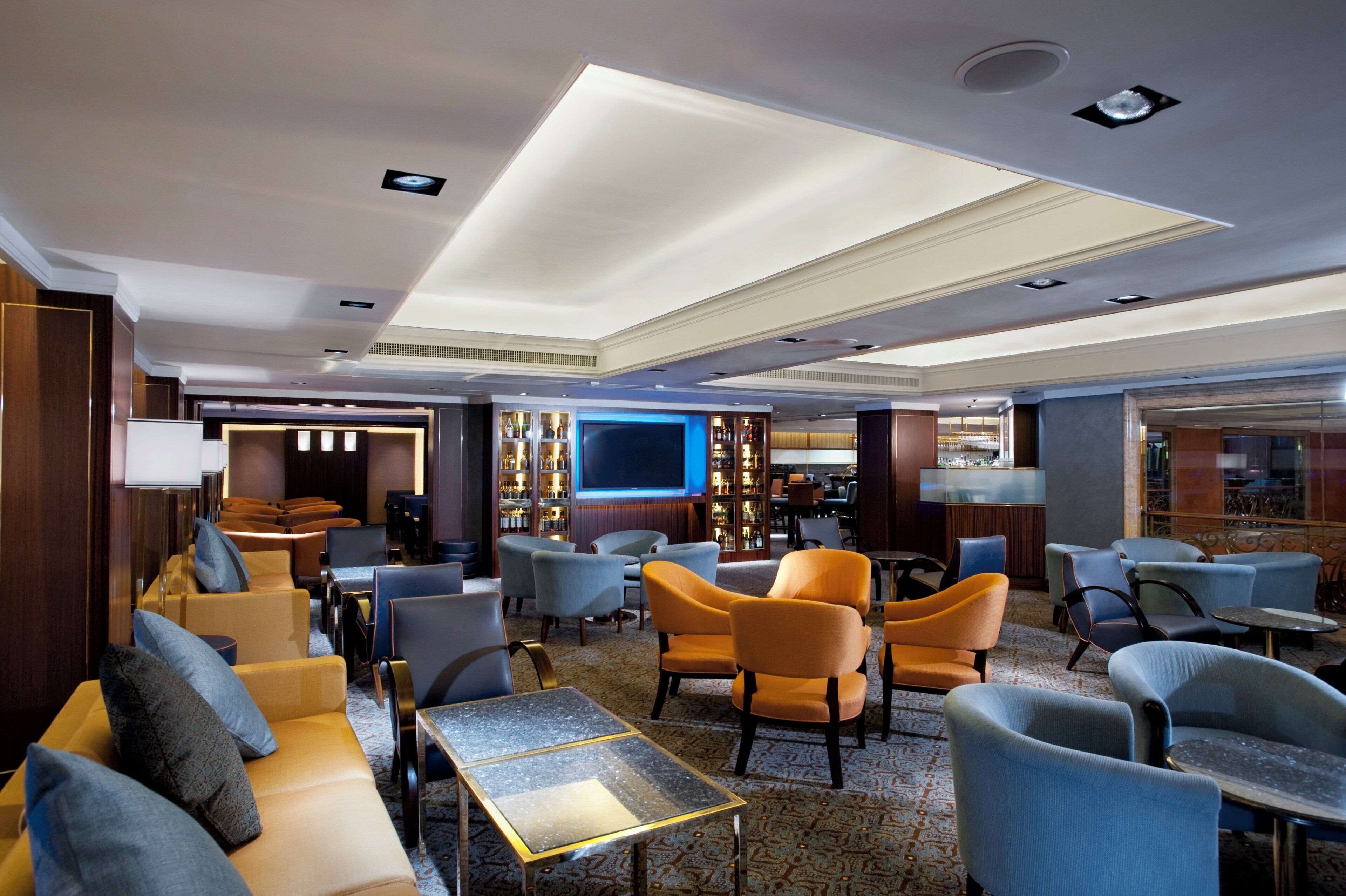 A hotel lobby with seating areas, a bar, and a television screen.