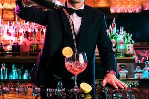 Un barman verse une boisson dans un verre rempli de glaçons et garni d’une tranche de citron.