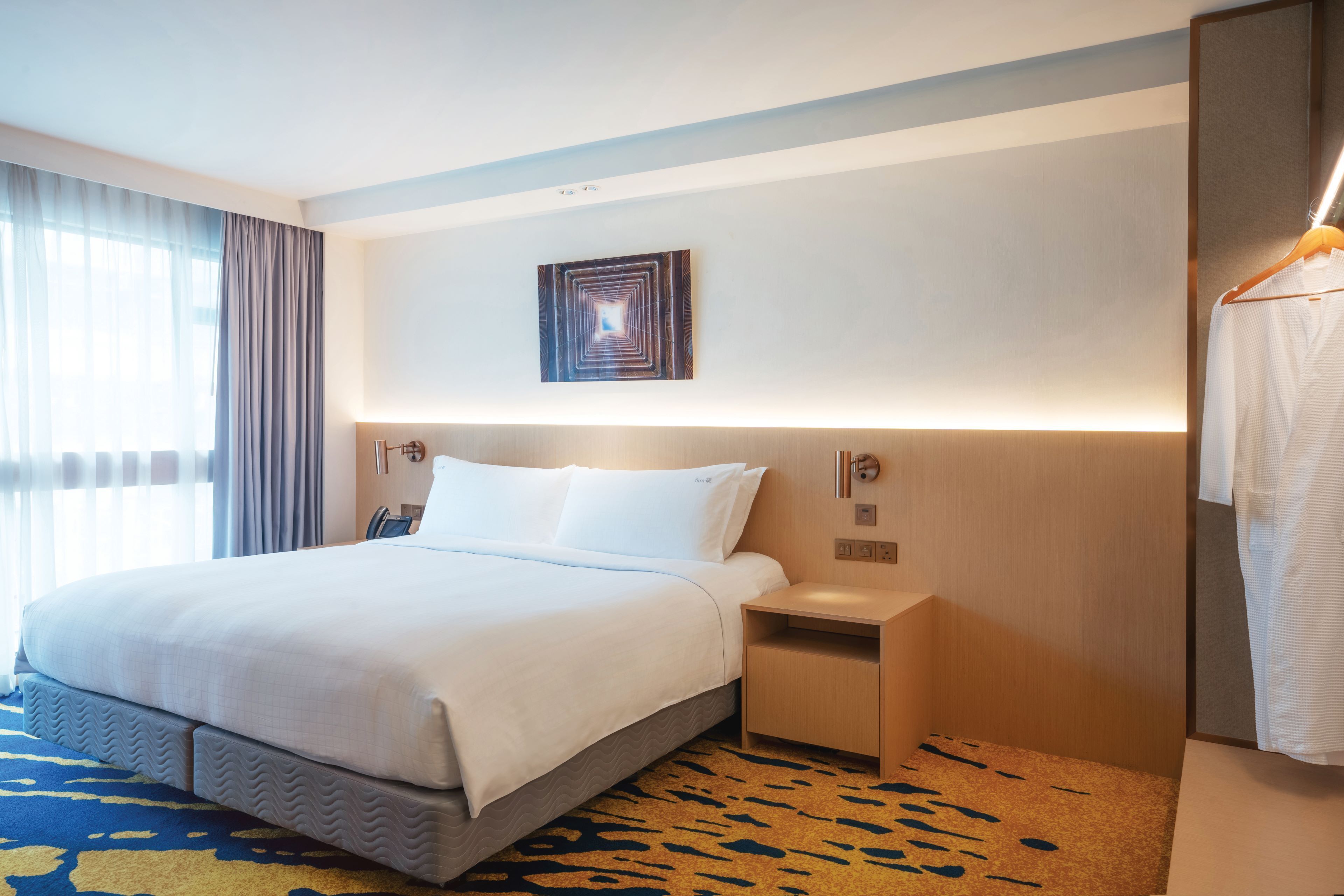 Une chambre d’hôtel avec un grand lit, des tables de chevet, un porte-serviettes mural et une œuvre d’art accrochée au mur.