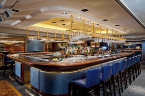 A bar area with a long counter, blue upholstered bar stools, and a ceiling with recessed lighting. - Holiday Inn Golden Mile Hong Kong by IHG (Kowloon)