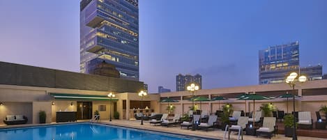 Una piscina al aire libre, sombrillas, sillones reclinables de piscina