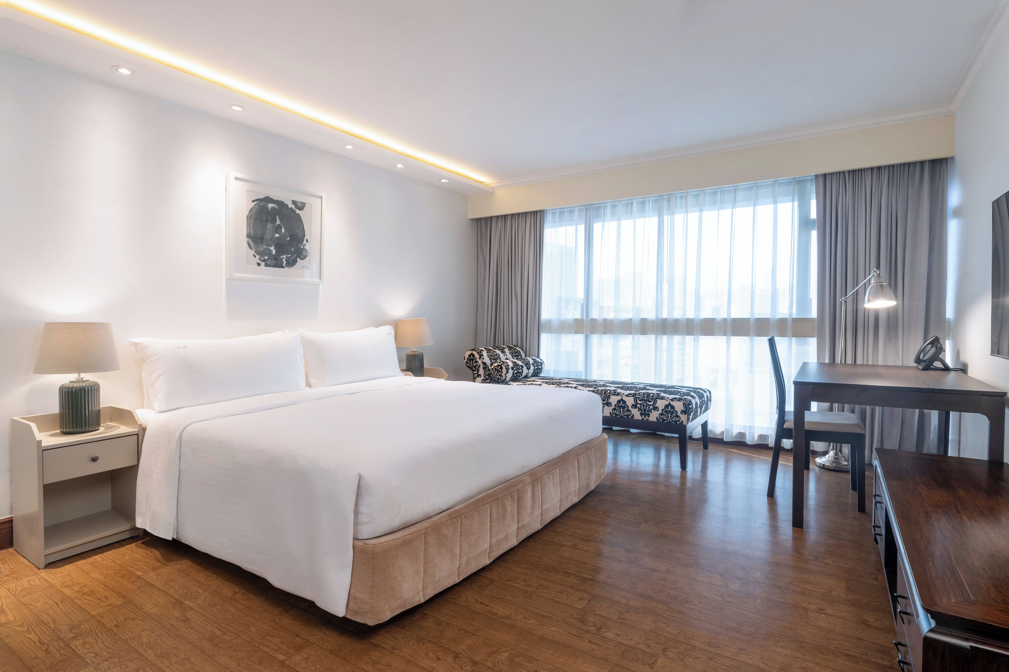 Une chambre d’hôtel moderne, dotée d’un grand lit, de tables de chevet, d’un bureau et d’une chaise.