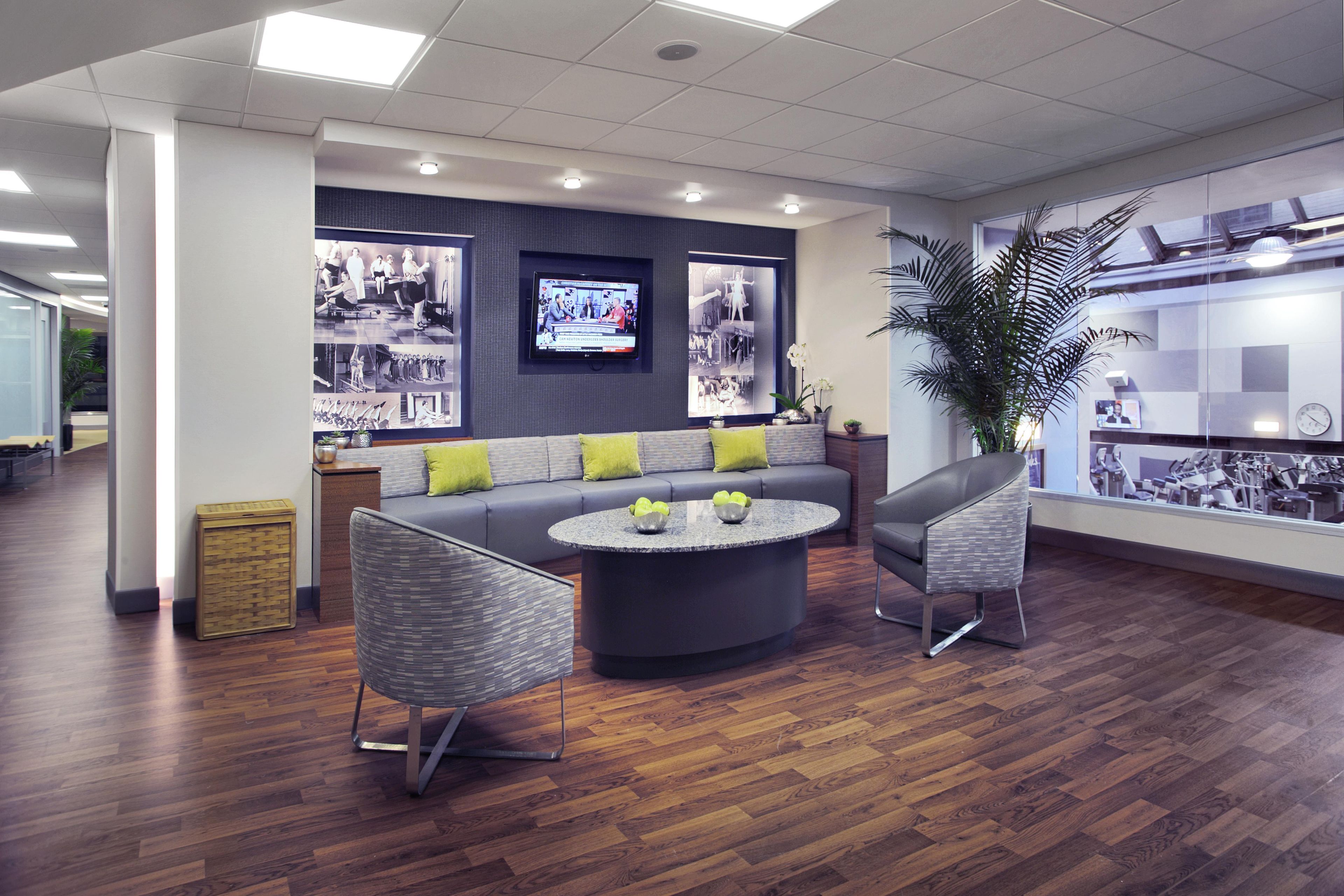 A modern lobby with a sofa, chairs, a coffee table, a TV, and a large plant.