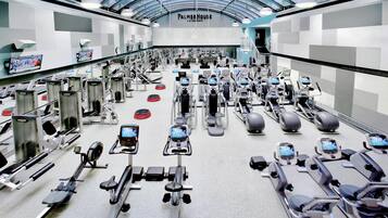 A gym with various exercise equipment, a large mirror, and a ceiling with a glass structure.