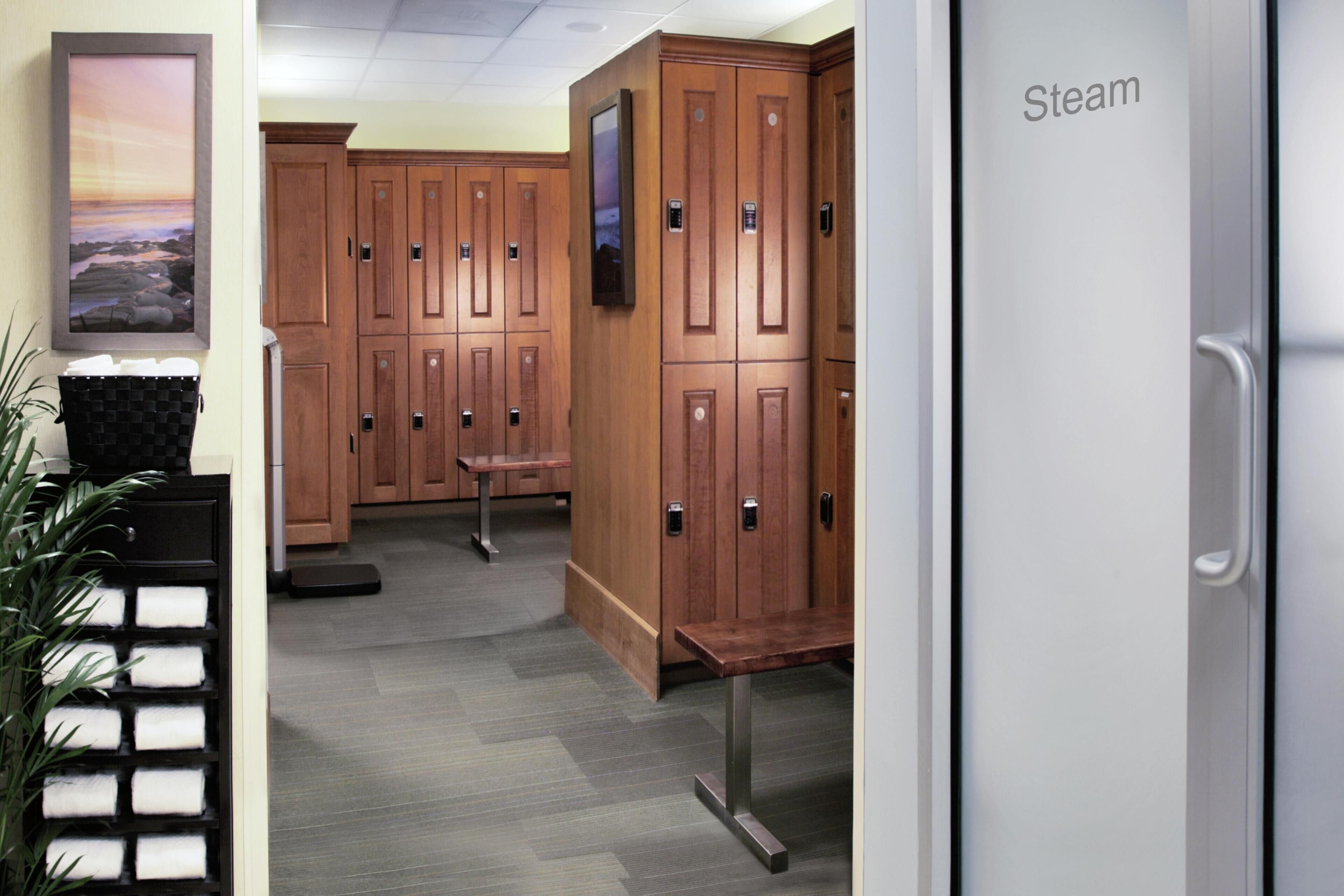 A hotel lobby with wooden lockers, a bench, a scale, and a framed picture on the wall.