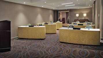 Uma área de recepção de hotel com design moderno, incluindo um balcão de atendimento, cadeiras e piso coberto de carpete.