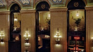 Eine beeindruckende Lobby mit aufwendigen Deckenmalereien, Kronleuchtern und einem gut sichtbaren 'P'-Emblem.