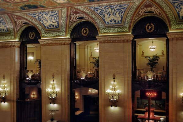 A grand lobby with ornate ceiling artwork, chandeliers, and a prominent 'P' emblem. - Palmer House a Hilton Hotel (Chicago)