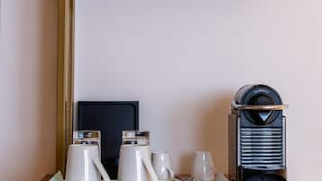 Una kitchenette con cafetera, hervidor de agua y un plato de comida sobre una encimera de madera.