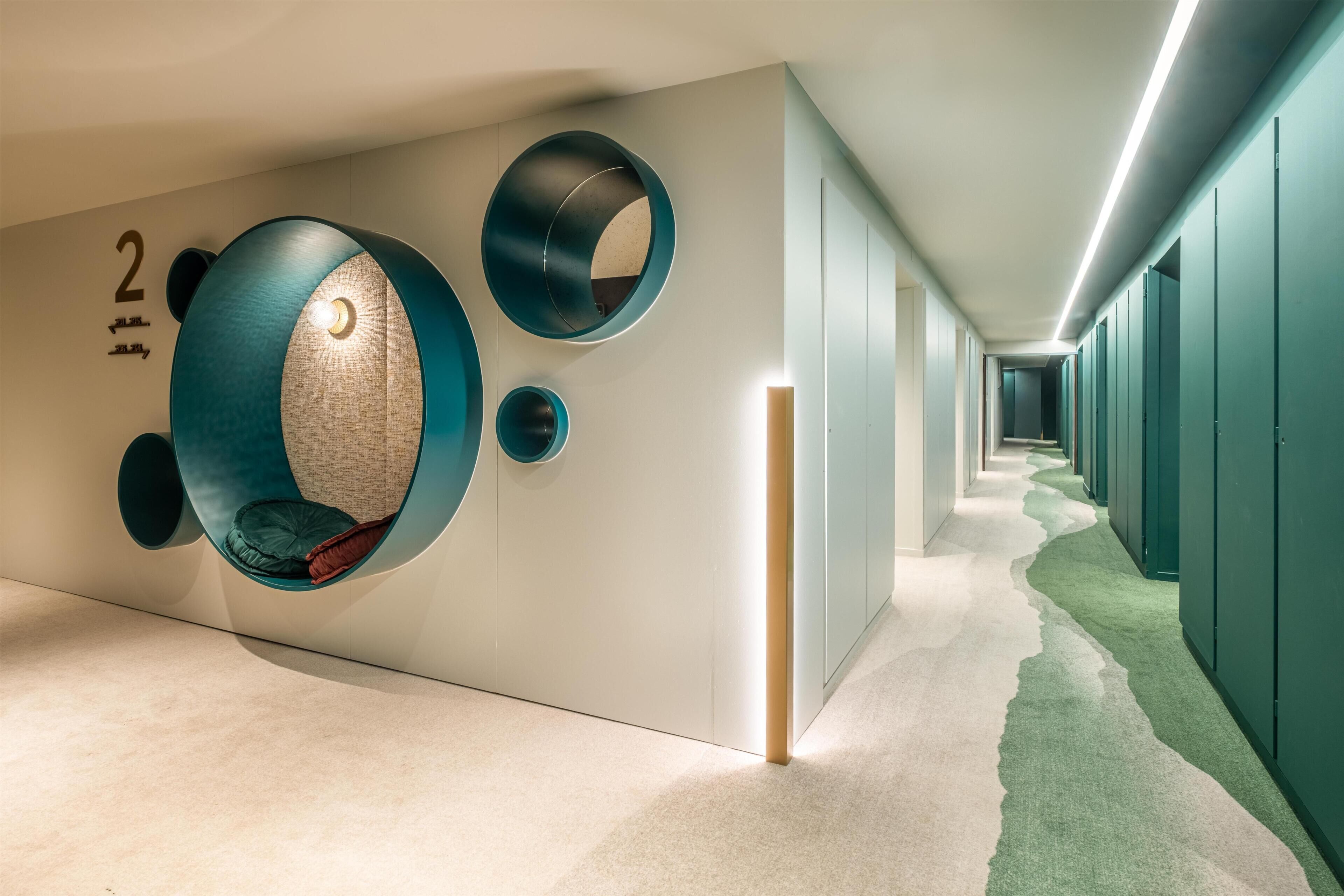 Un couloir avec des espaces de repos circulaires, un panneau indiquant le numéro « 2 » et un sol recouvert de moquette.