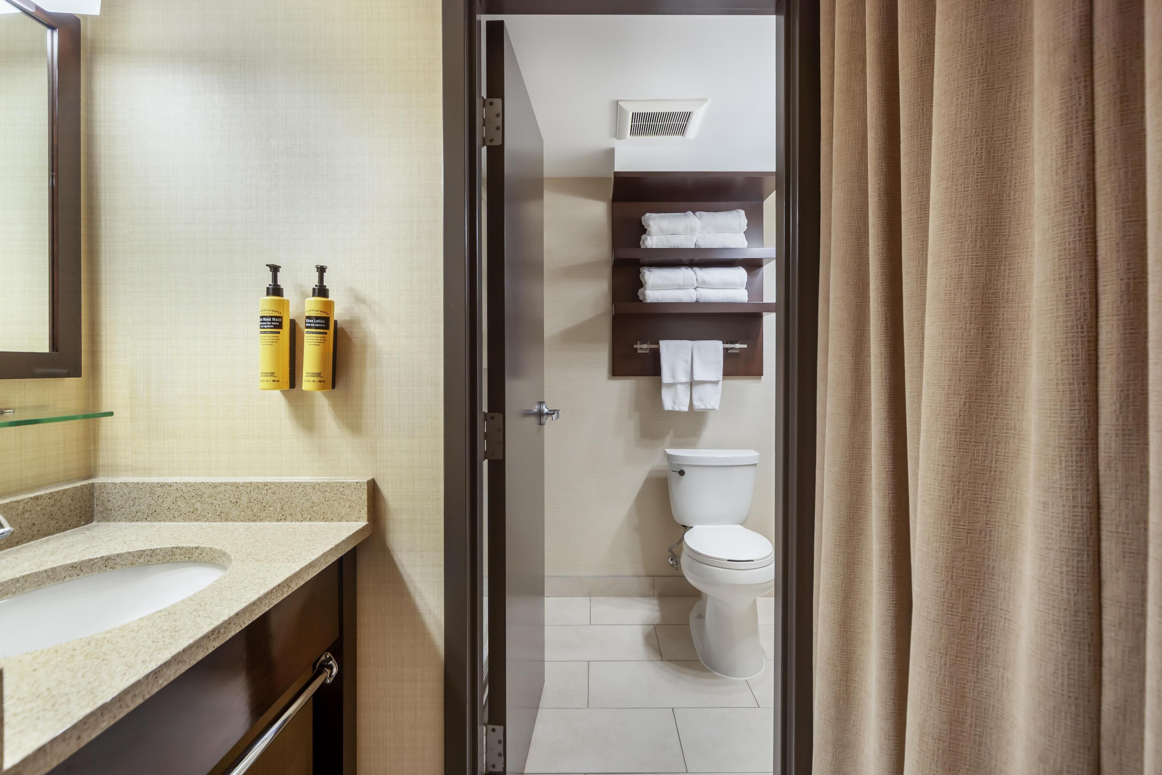 A bathroom with a sink, toilet, and shelves with towels.