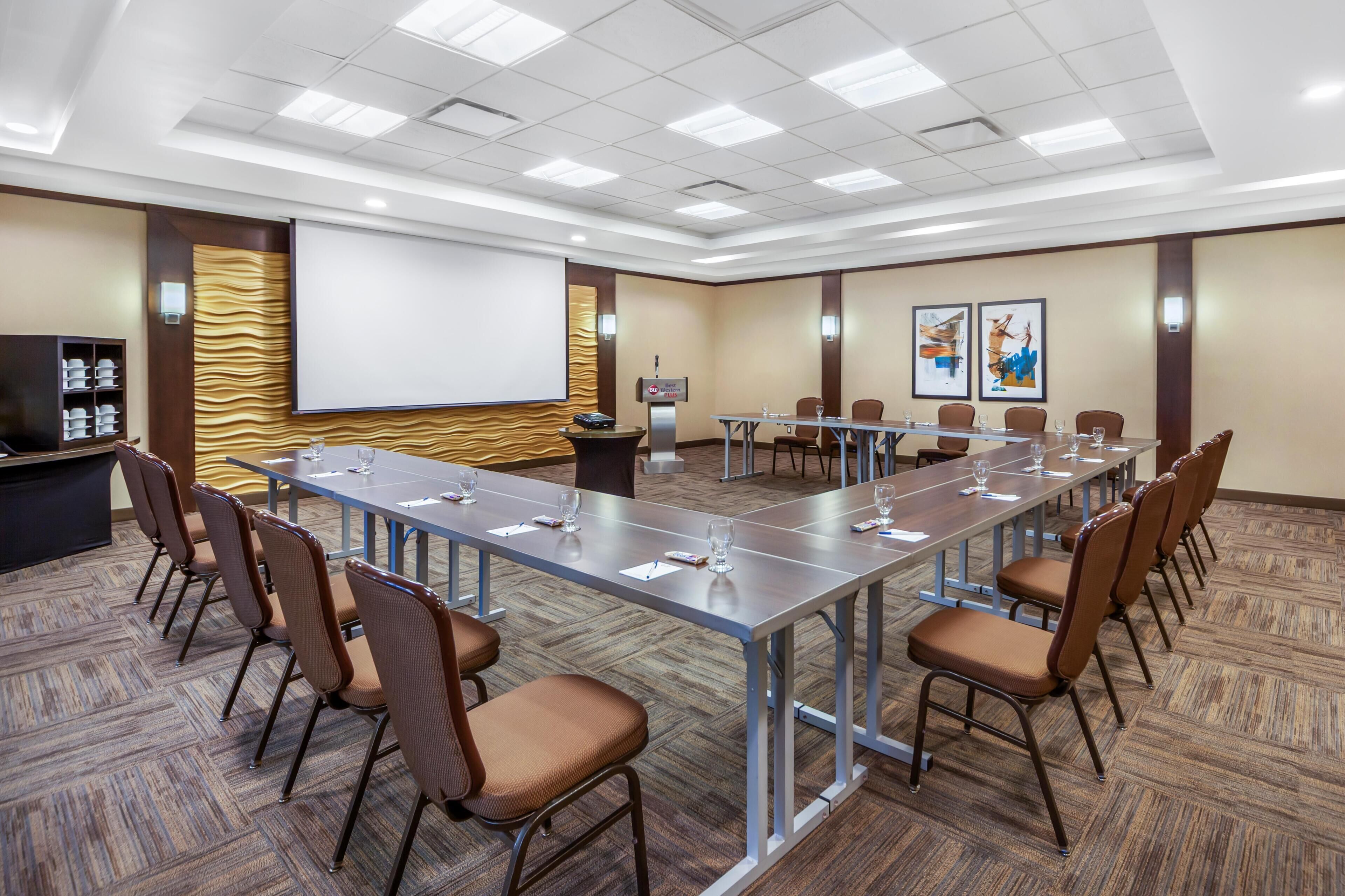 Una sala de conferències amb una taula llarga, cadires, una pantalla de projector i un atril.