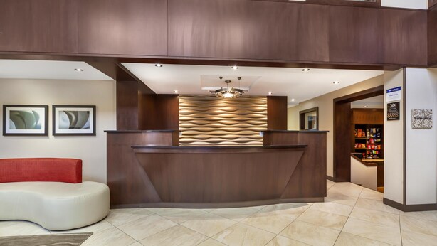 A reception area with a modern design, a reception desk, a red sofa, and a wall with framed artwork.