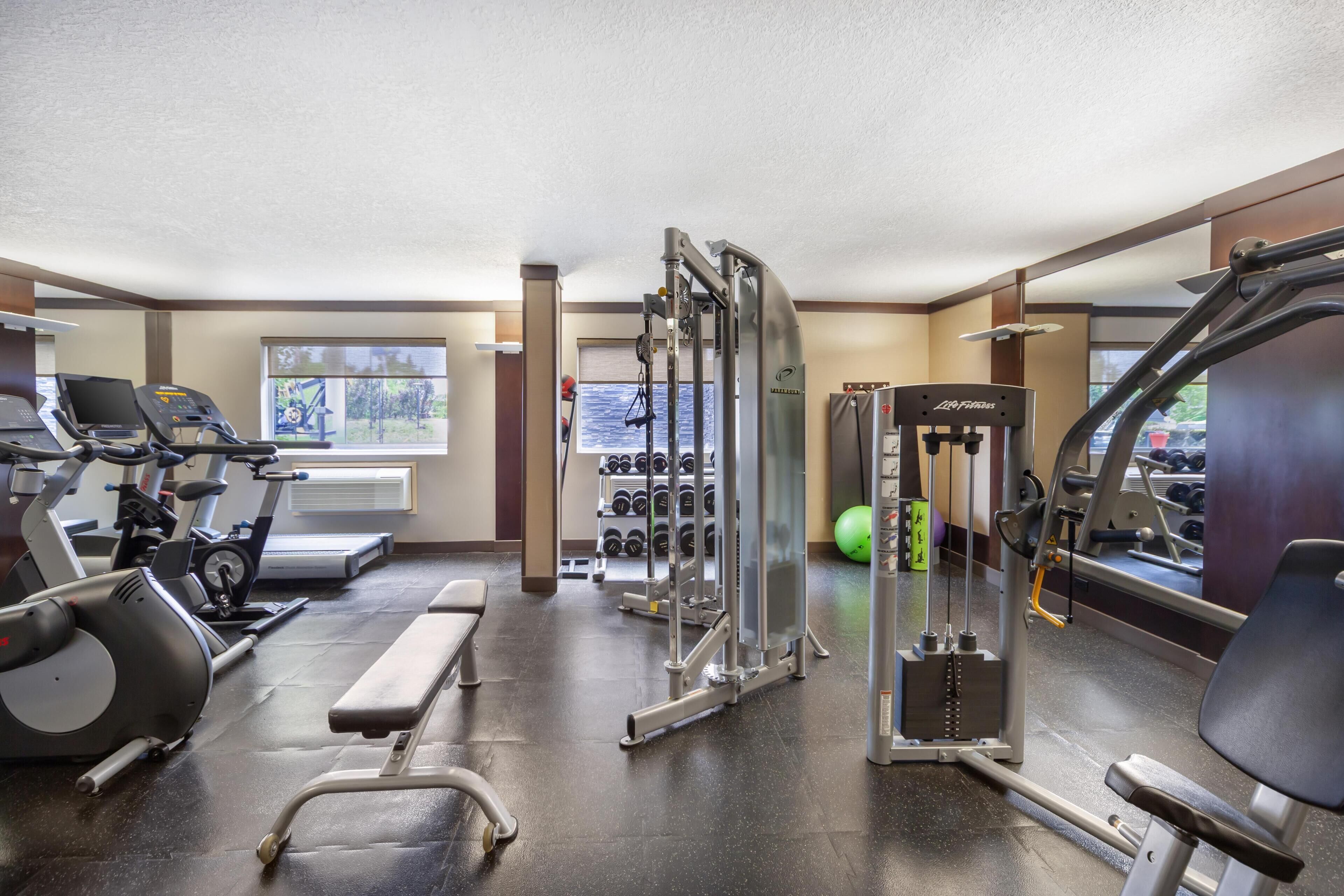 Ein Fitnessraum mit Trainingsgeräten, einer Bank und einem Fenster mit Blick.