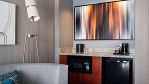 Una kitchenette compacta con microondas, cafetera y refrigerador pequeño.
