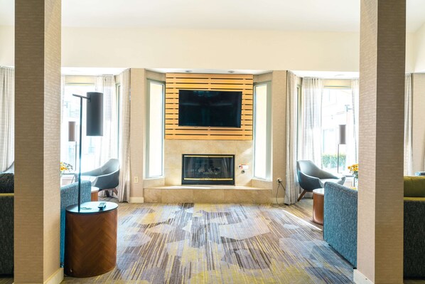 Un salon moderne avec une cheminée, des sièges confortables et un grand téléviseur.
