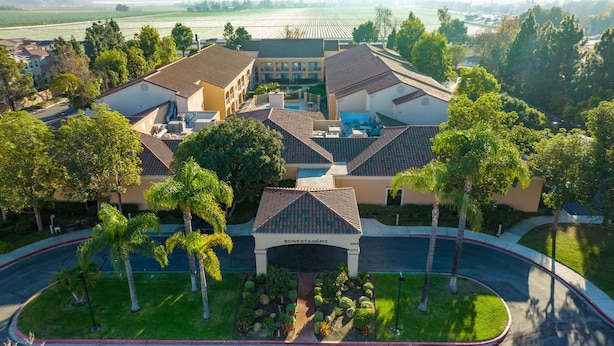 Vista aérea de un complejo residencial con varios edificios, una piscina y jardines bien cuidados.