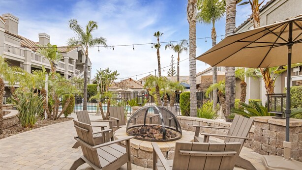 A patio area with Adirondack chairs, a fire pit, and a pool in the background. - Sonesta ES Suites Chatsworth (Chatsworth)