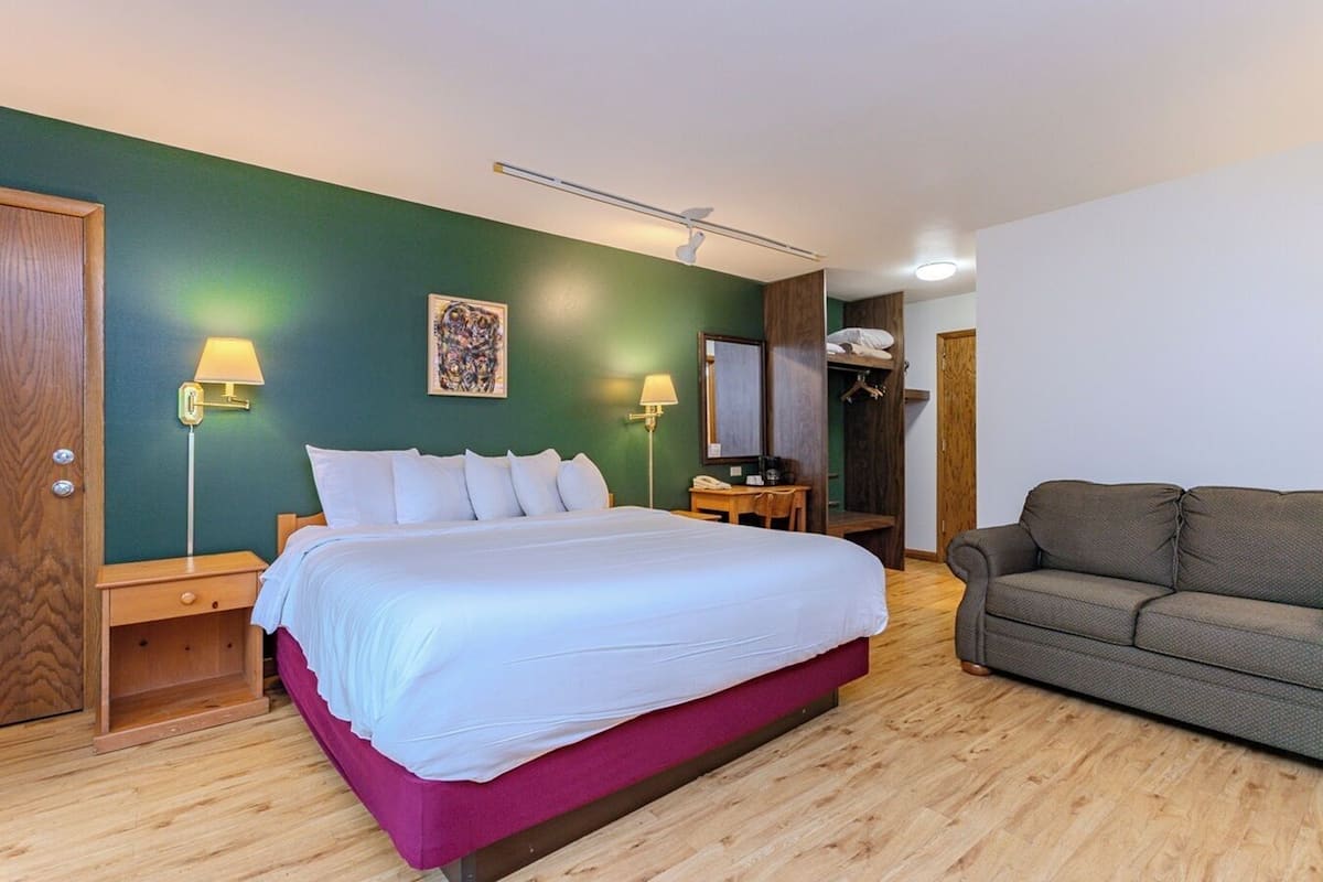 A hotel room with a bed, a sofa, a desk, and a wardrobe.
