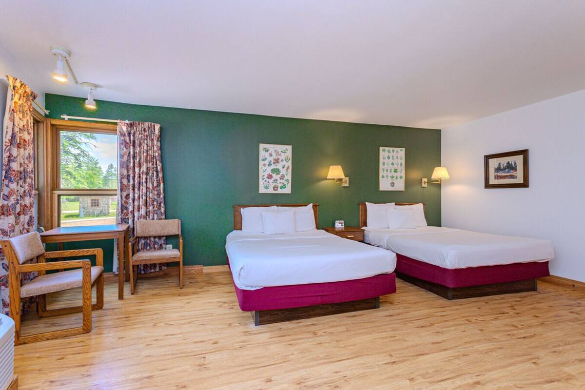 A room with two beds, a desk, and a chair.