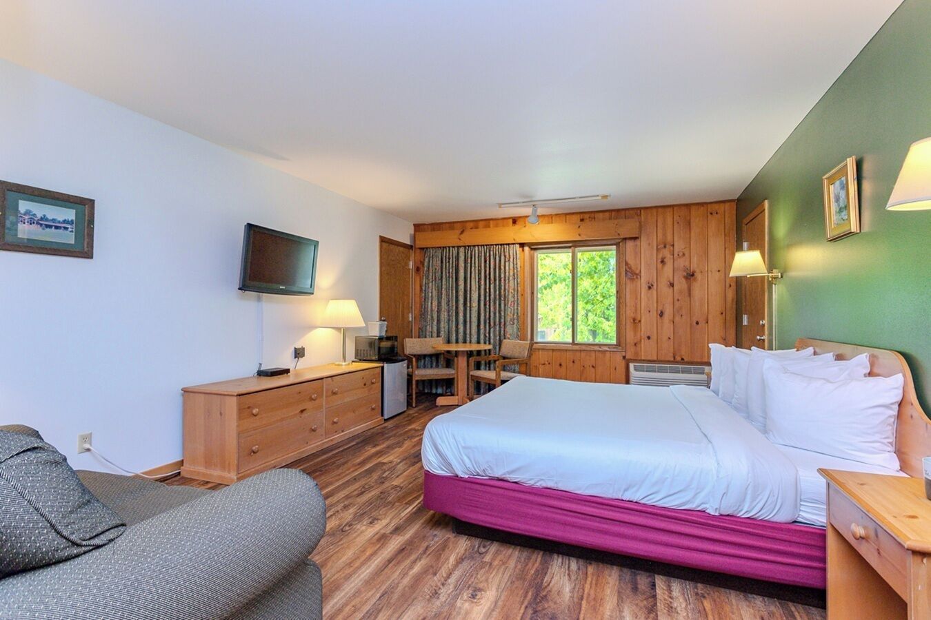 A hotel room with a bed, a desk, a chair, a television, and a window with curtains.