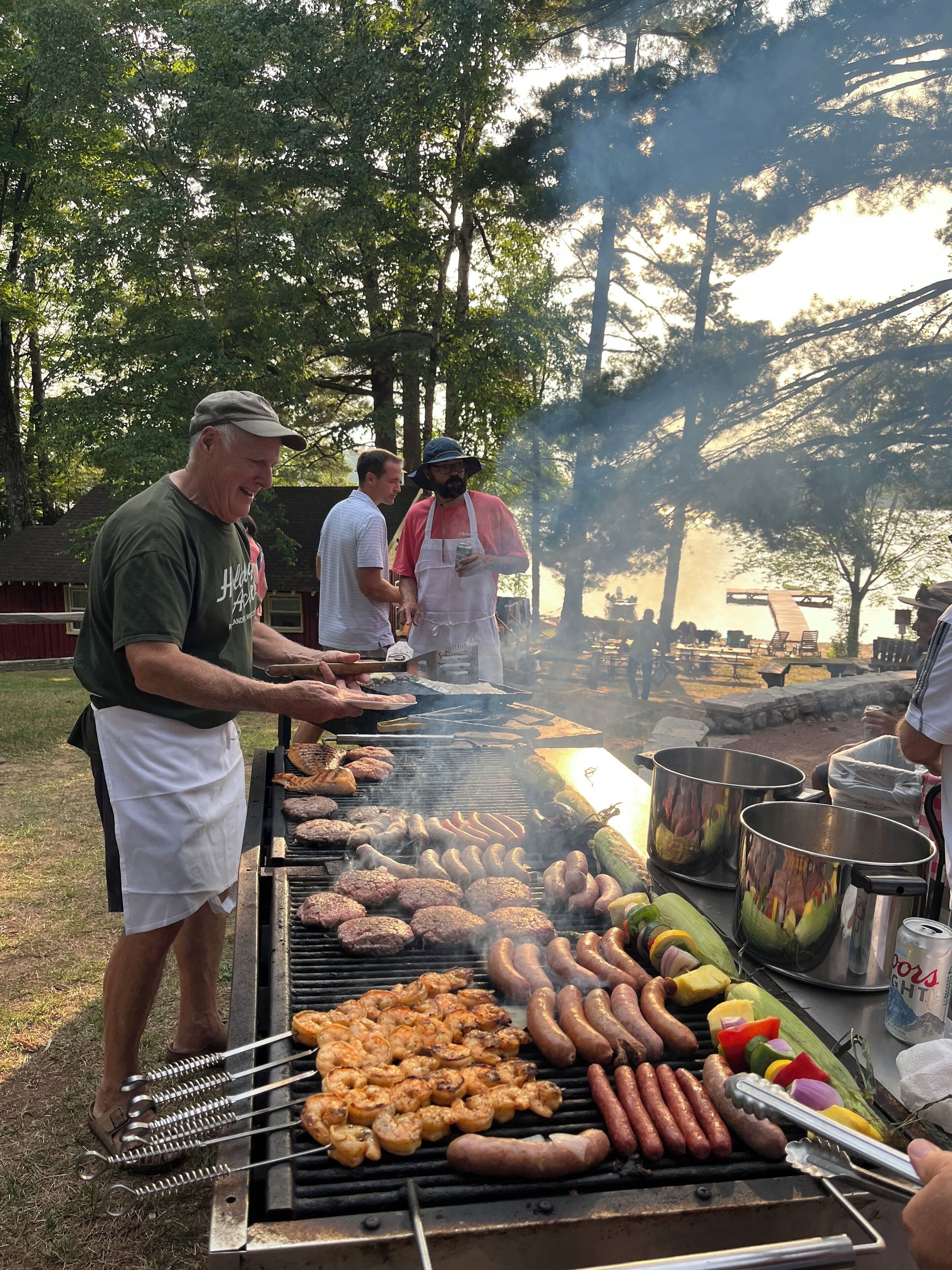 A barbecue with various meats and vegetables being grilled outdoors.
