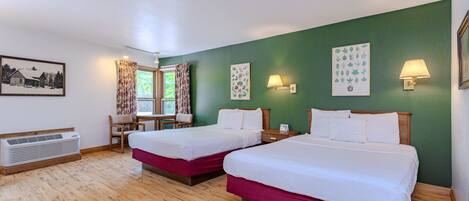 Quarto de hotel com duas camas, uma escrivaninha, cadeiras, uma janela com cortinas, luminárias de parede e um aquecedor.