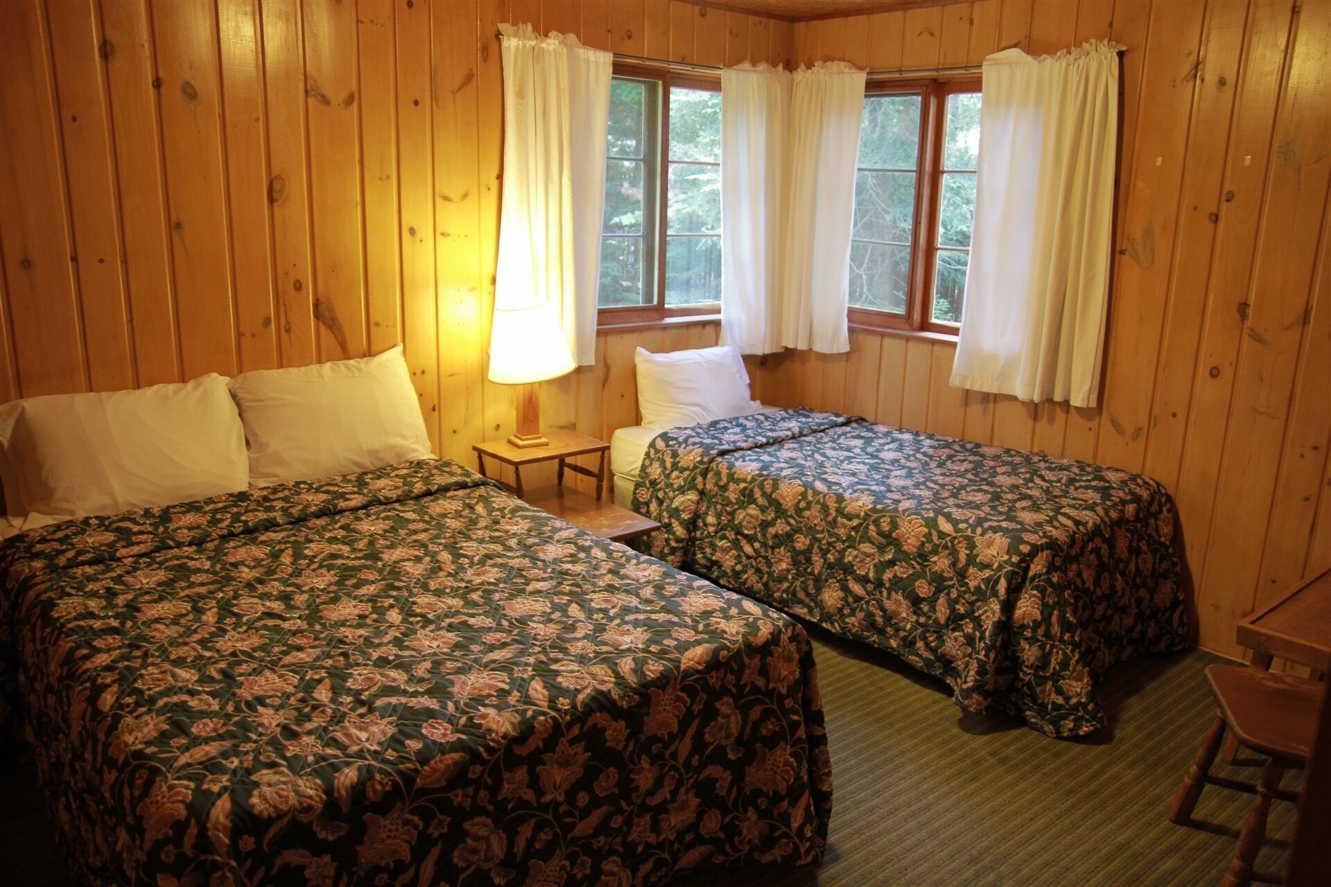 A room with two beds, a small table, and a chair.
