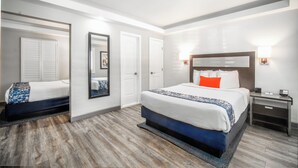 Una habitació d'hotel moderna amb un llit gran, una tauleta de nit i un mirall.