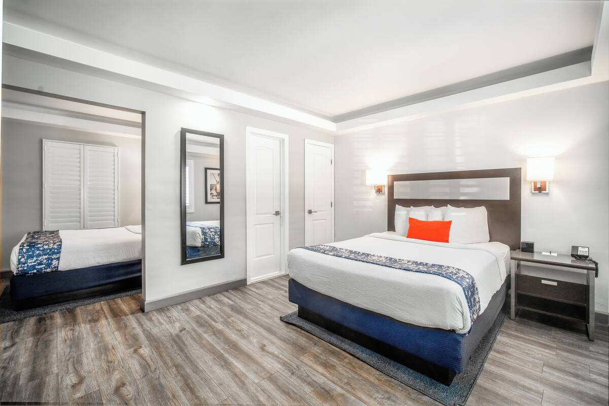 A modern hotel room with a large bed, a nightstand, and a mirror.